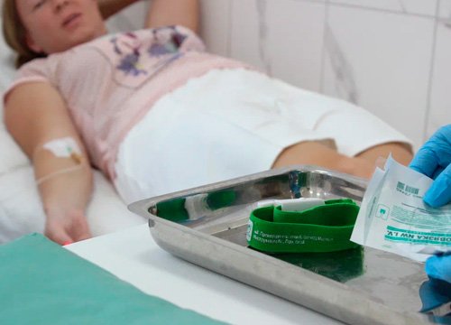 Пациент лежит с подключенной капельницей к руке